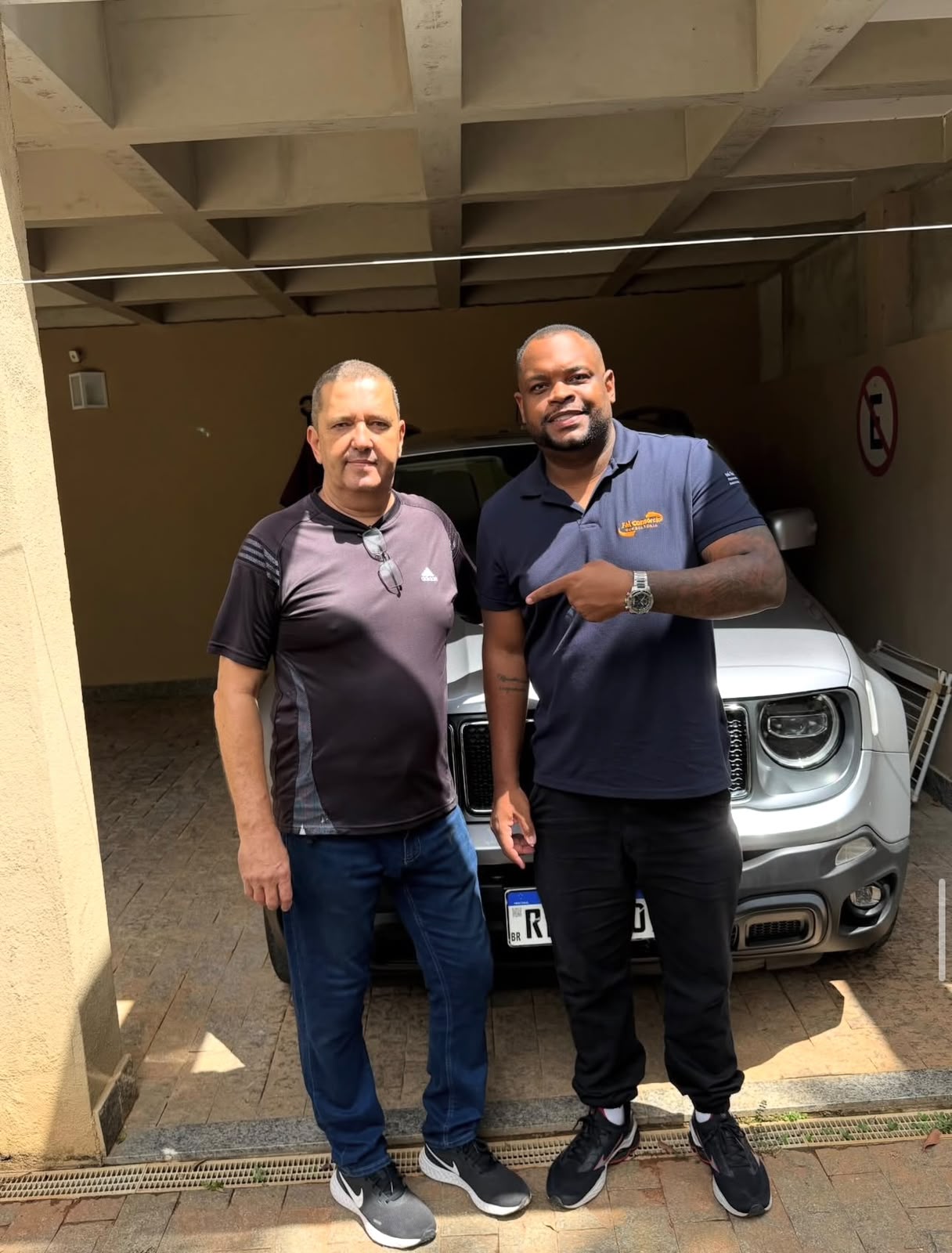 Cliente ao lado do seu SUV prata com o consultor da FM Consórcios