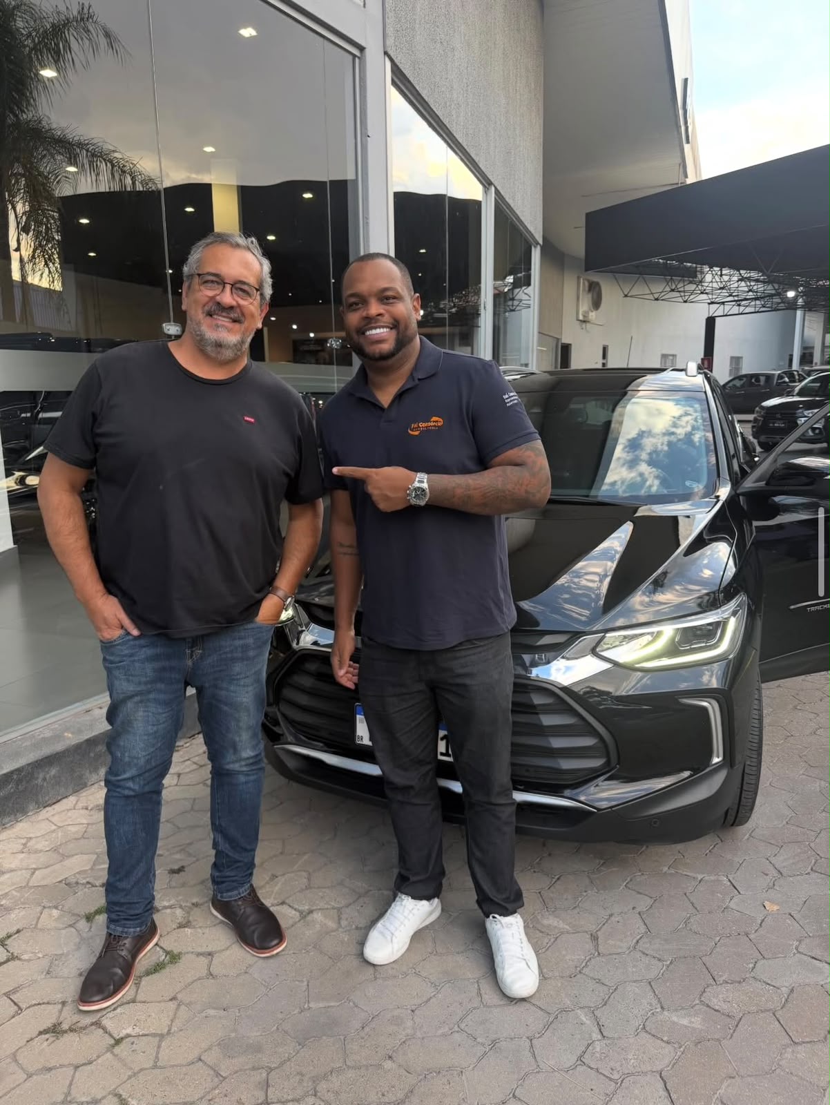 Cliente ao lado do seu SUV preto em frente à concessionária